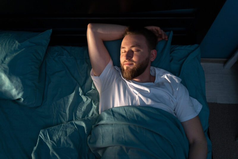 Top view of handsome young man sleeping on a bed in his bedroom at night. resting, good night sleep